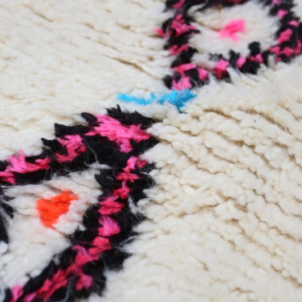 Berber Teppich Detail mit schwarzem und pinkem Muster auf cremefarbener Wolle