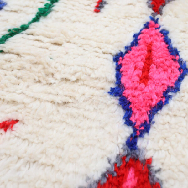 Detail eines Azilal Teppichs mit pinkem Berber-Muster auf cremefarbener Wolle