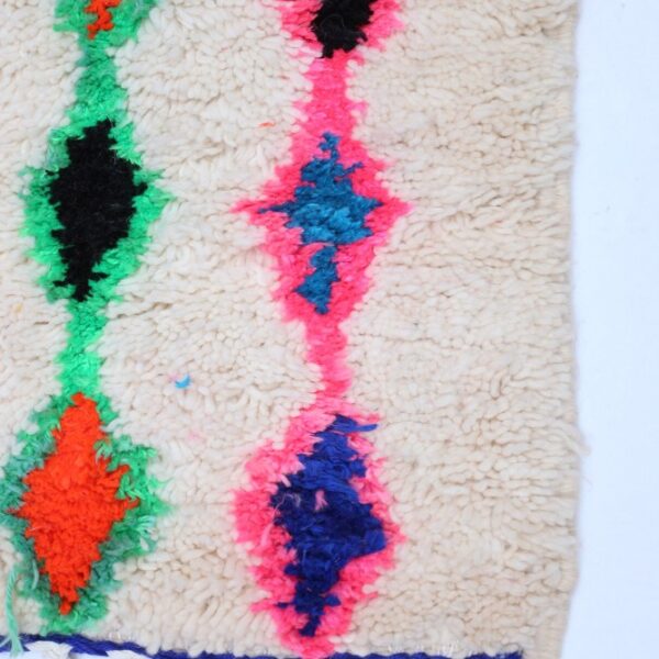 Ecke eines Berber Teppichs mit Fransen und bunten Diamantmotiven