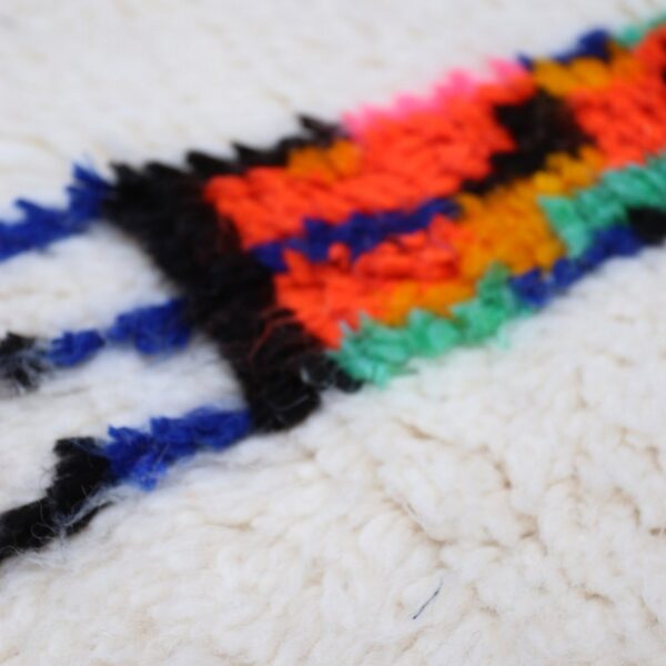 Nahaufnahme eines Azilal Teppichs mit schwarzem Linienmuster und bunten Details auf Wolle