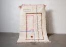 Berber Teppich aus Marokko mit rosa und blauen Linien auf cremeweißem Hintergrund